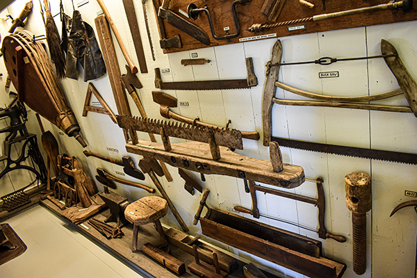 a wall displaying old saws and other tools from the time